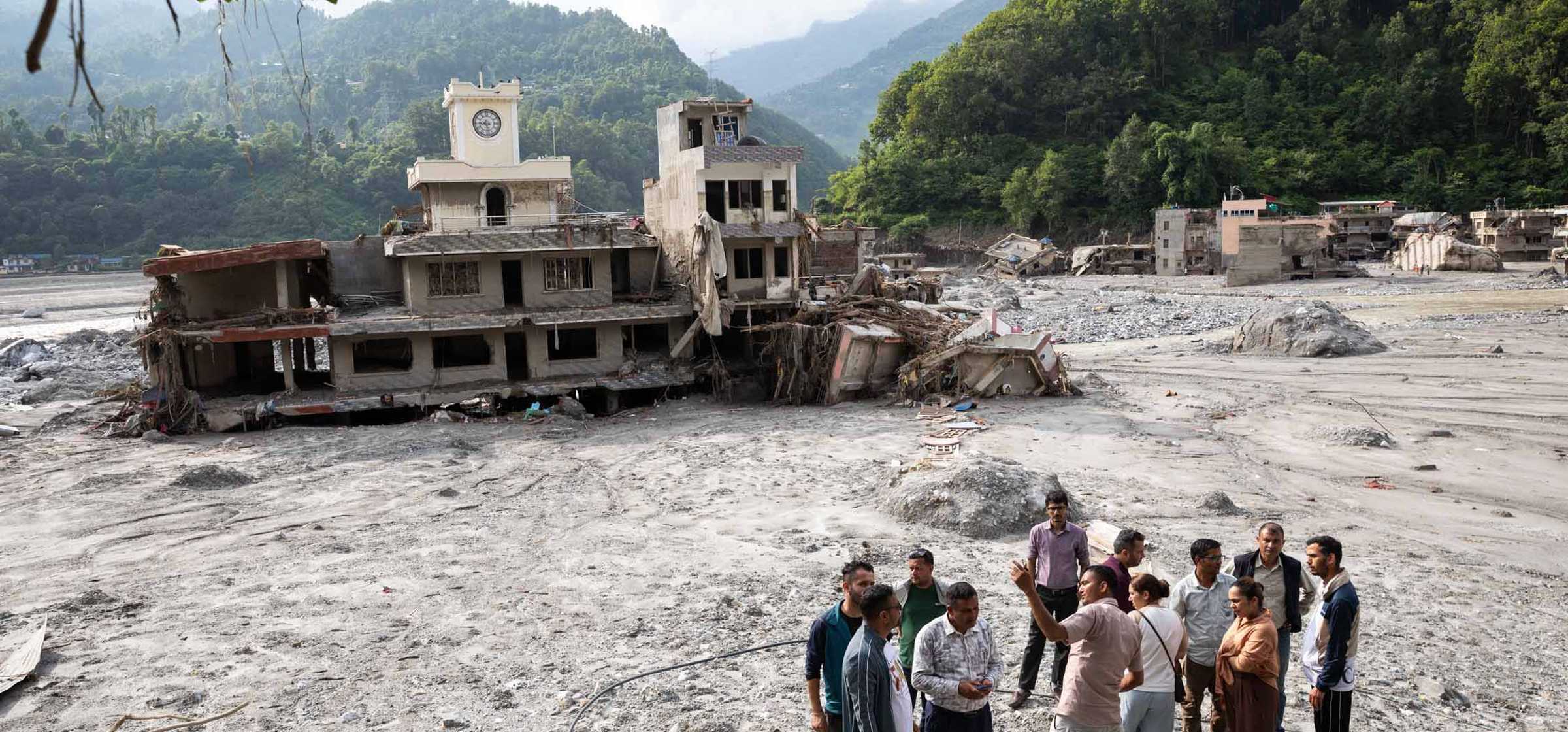 People stand near houses deluged in sludge.jpg